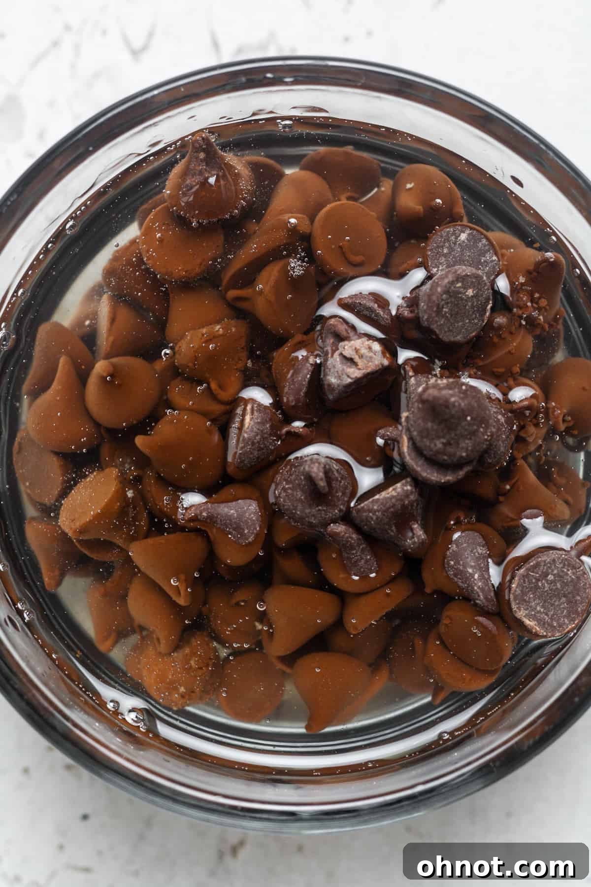 Dark chocolate chips and coconut oil in a bowl before melting.