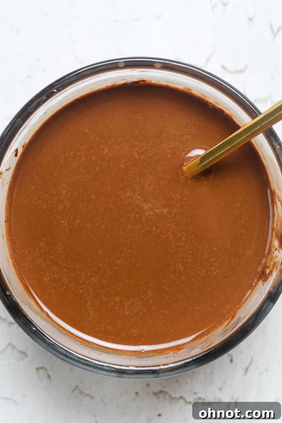 Melted dark chocolate and coconut oil, smooth and glossy, in a microwave-safe bowl.