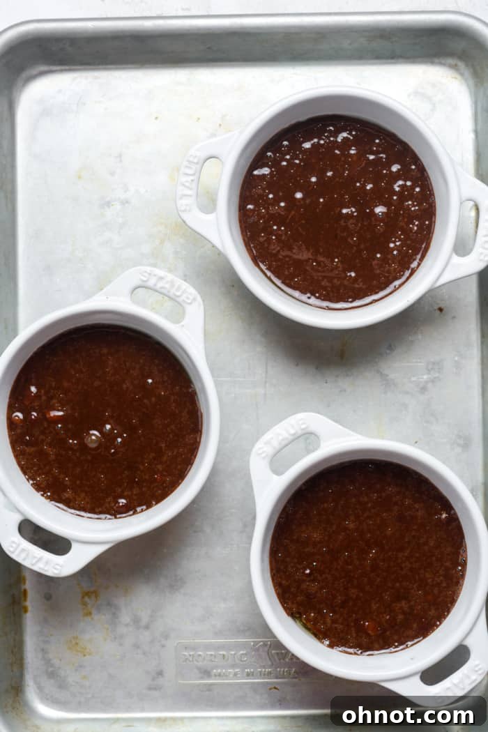 Three ramekins filled with rich chocolate cake batter, ready for baking.