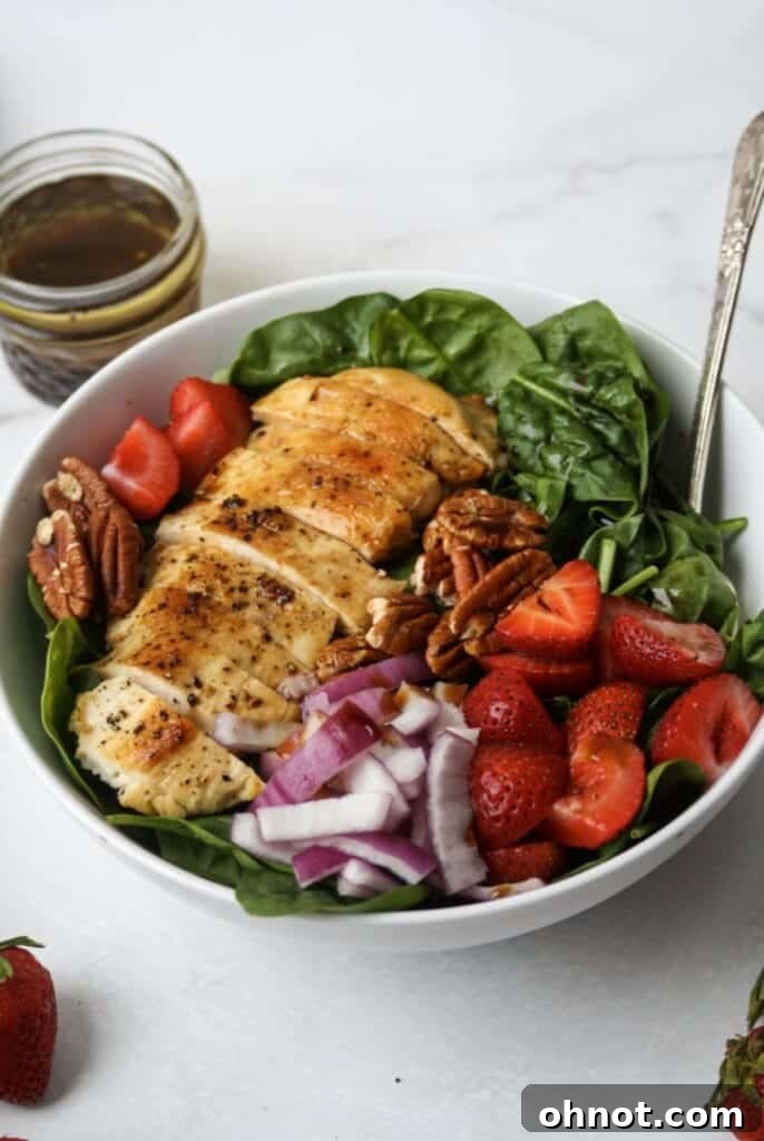 Close-up of a salad with grilled chicken, strawberries, and pecans, highlighting the vibrant colors and fresh ingredients