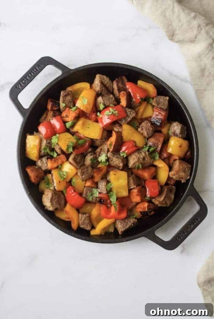 Delicious Whole30 Garlic Steak Bites served with sweet potatoes and bell peppers in a cast iron skillet, ready to be enjoyed.
