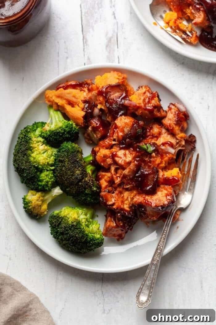 A serving of Whole30 BBQ Chicken Casserole on a white plate with a side of fresh broccoli.