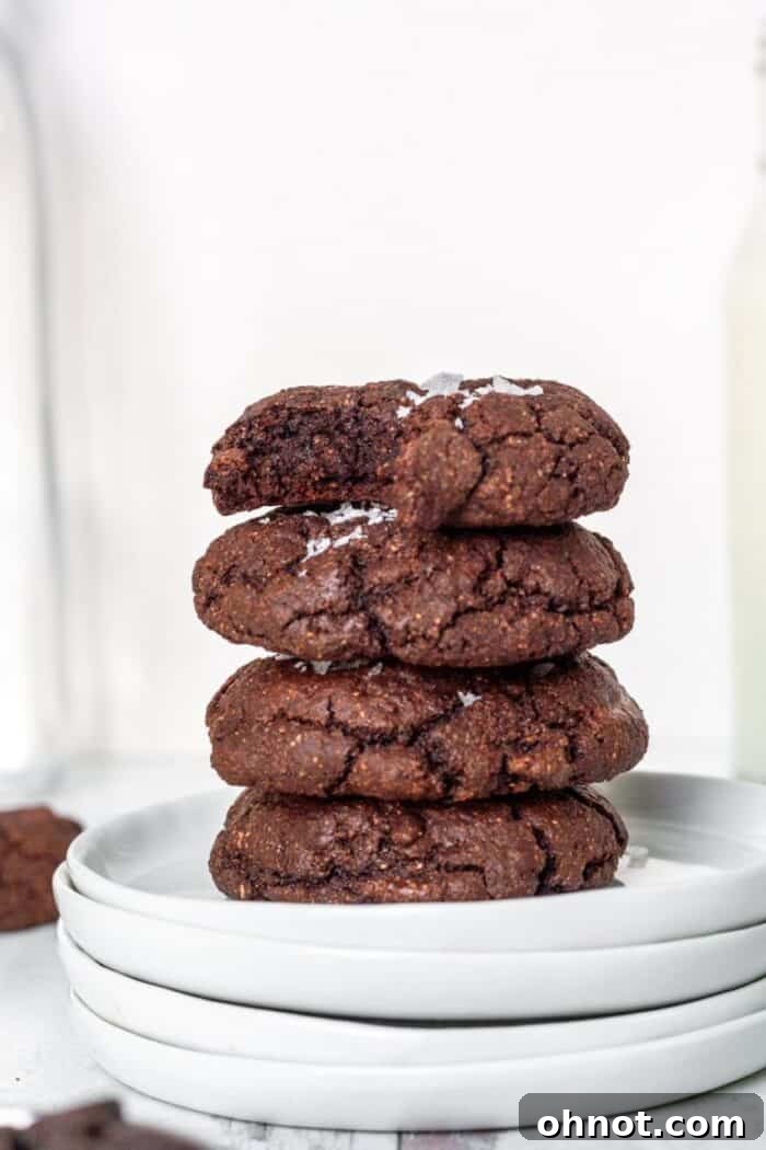 A stack of Paleo Brownie Cookies on a white plate, showcasing their rich, dark color and crinkly tops.