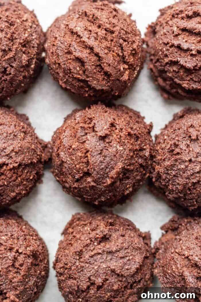 Paleo Brownie Cookie dough balls neatly arranged on a sheet of white parchment paper, ready to be baked.
