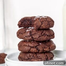 A stack of Paleo Brownie Cookies on a white plate, showcasing their rich, dark color and crinkly tops.