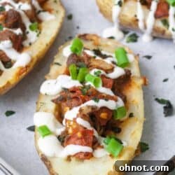 Whole30 potato skins filled with tomatoes, pepperoni and marinara sauce on a baking sheet