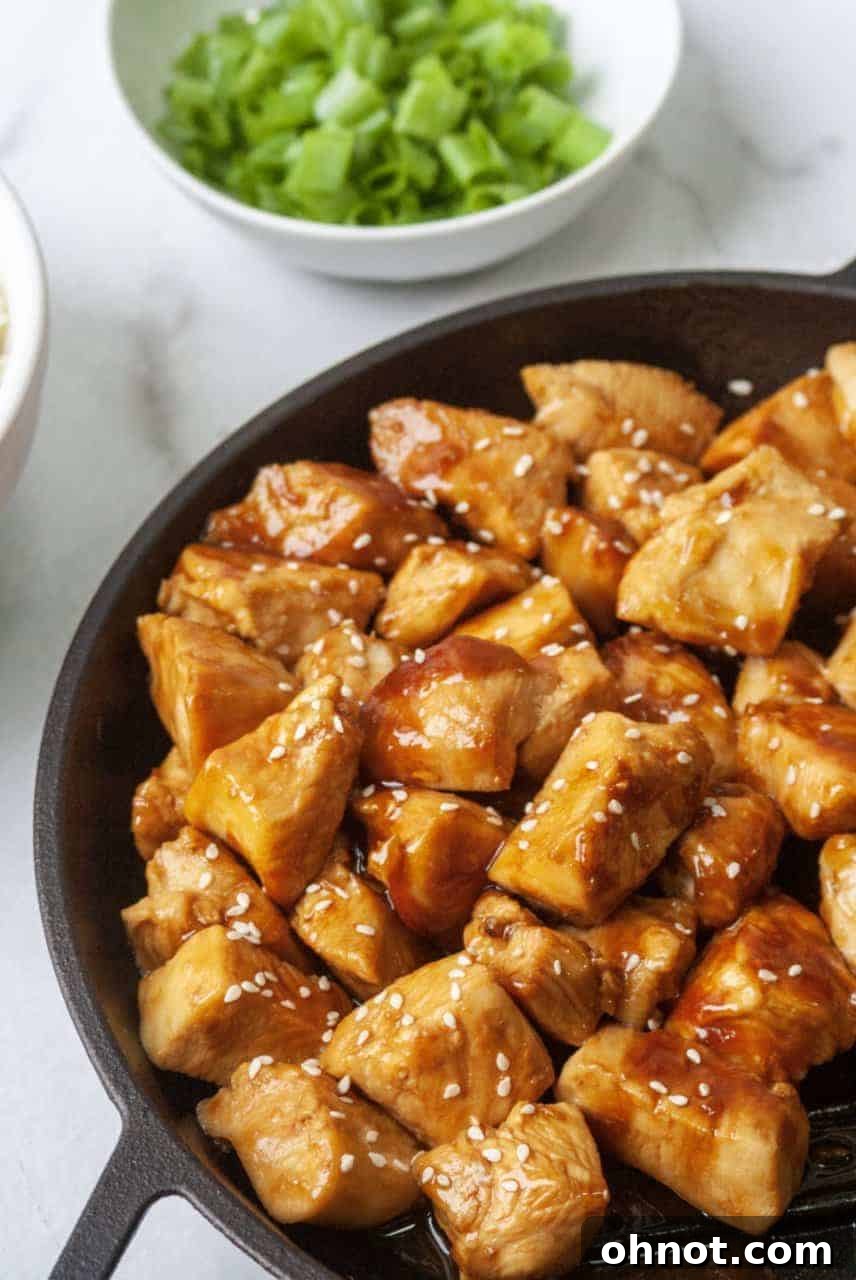 Close-up of golden-brown chicken pieces being sautéed in a pan with garlic, salt, and pepper.