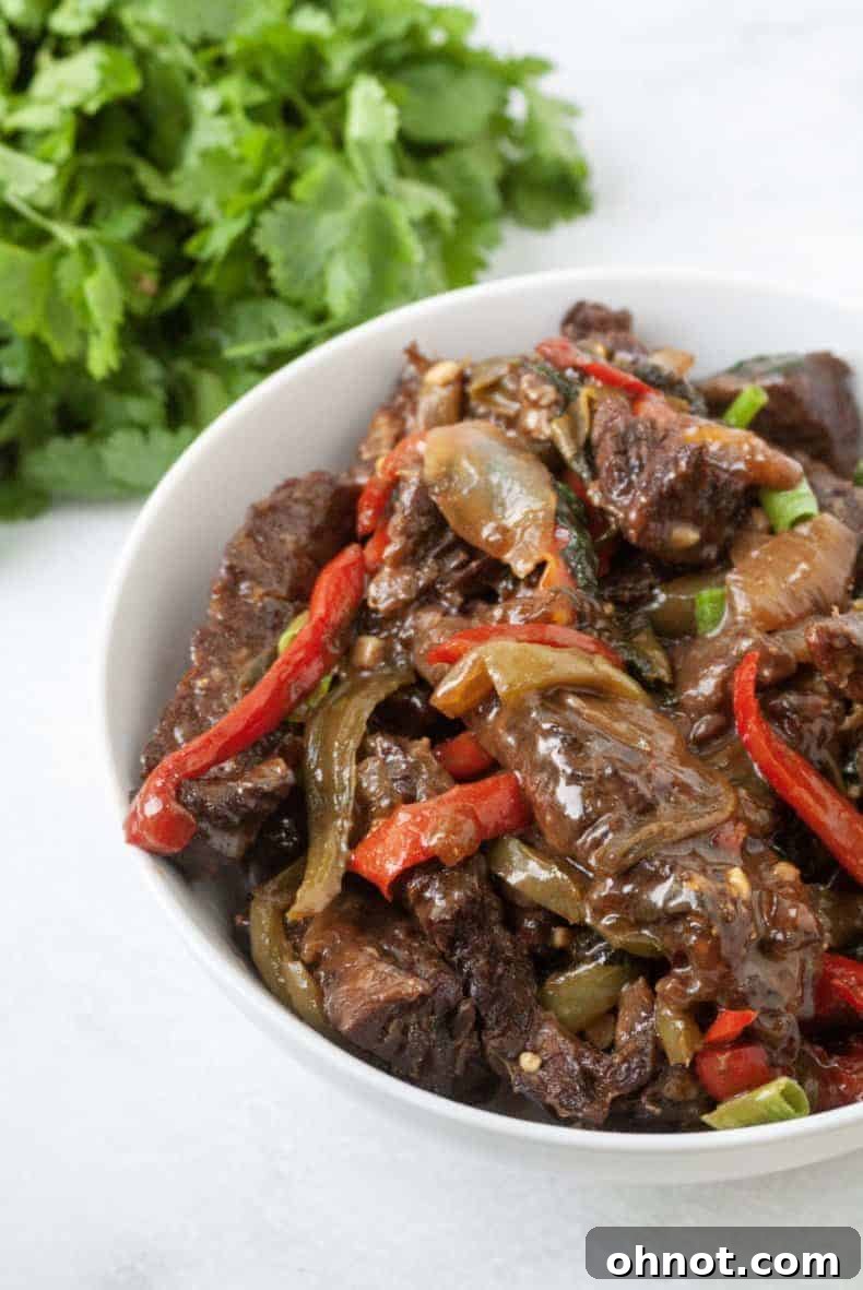 Close-up of Whole30 Thai Basil Steak, featuring tender beef and colorful bell peppers, expertly cooked in a pressure cooker pot.