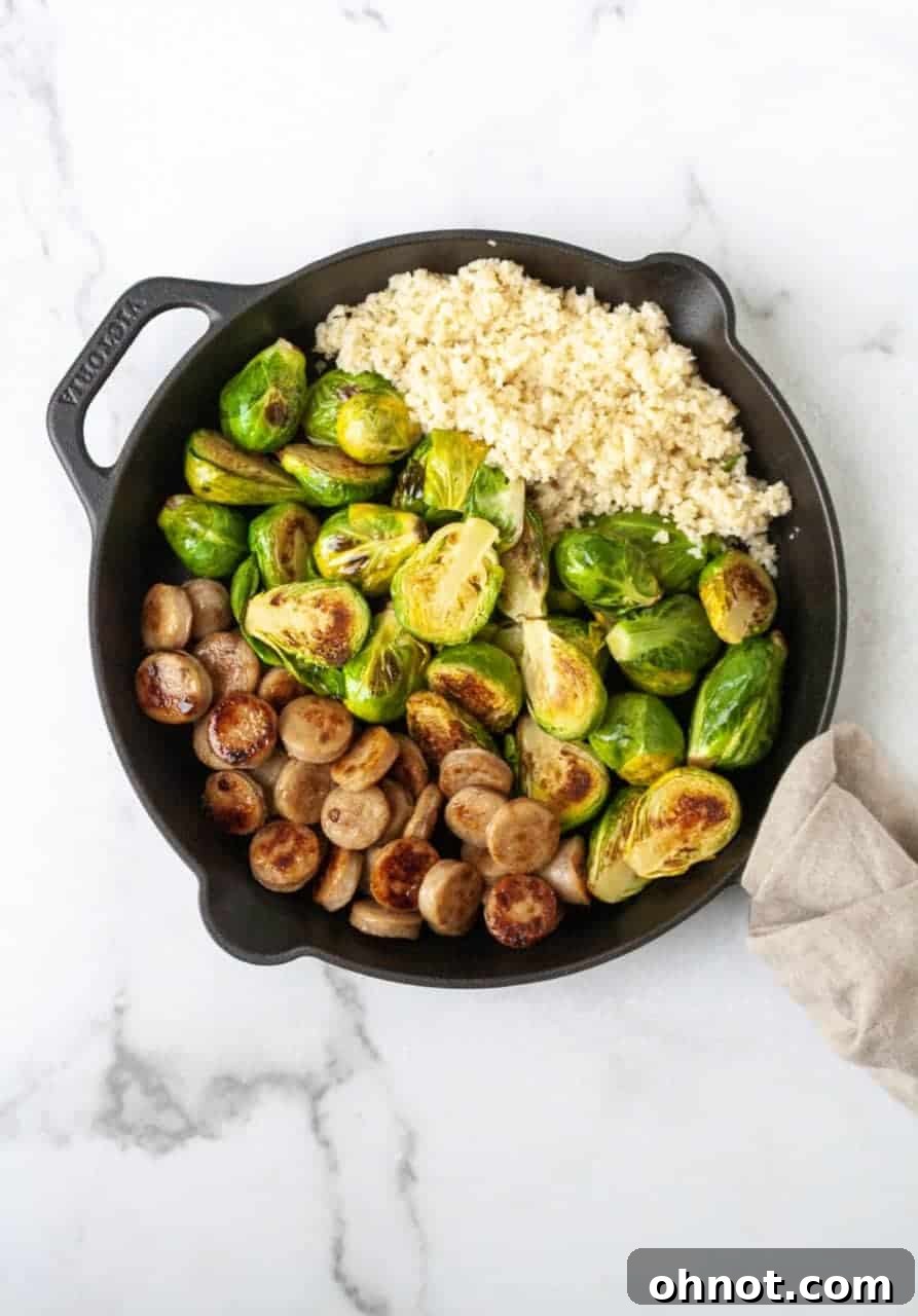 Close-up of Al Fresco chicken sausage slices and halved Brussels sprouts searing in a skillet with olive oil.