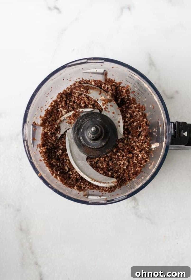 Close-up of the blended mixture in a food processor, showing a cohesive, dough-like texture for the energy bites.