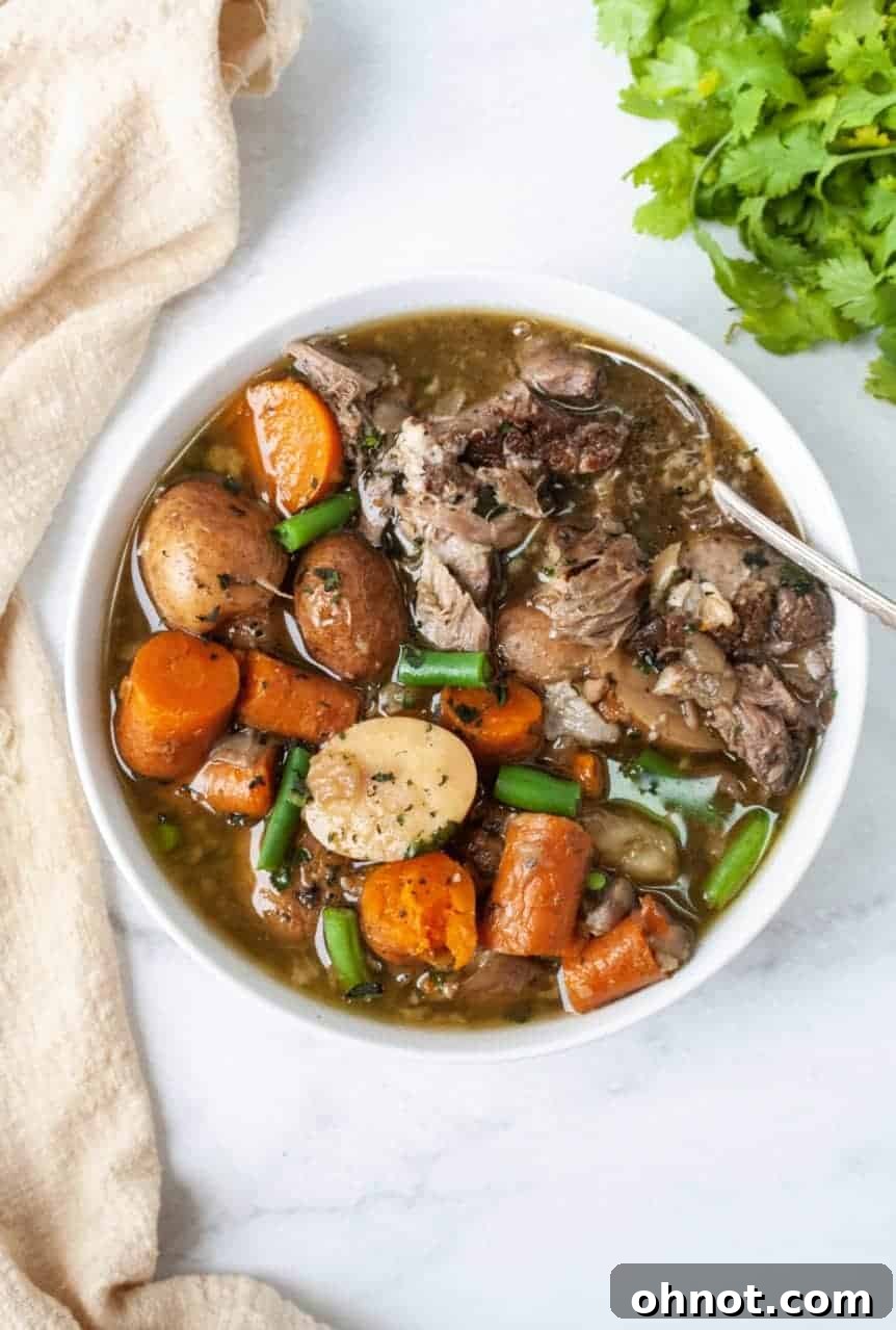A bowl of Whole30 Vegetable Pork Soup with fresh basil garnish