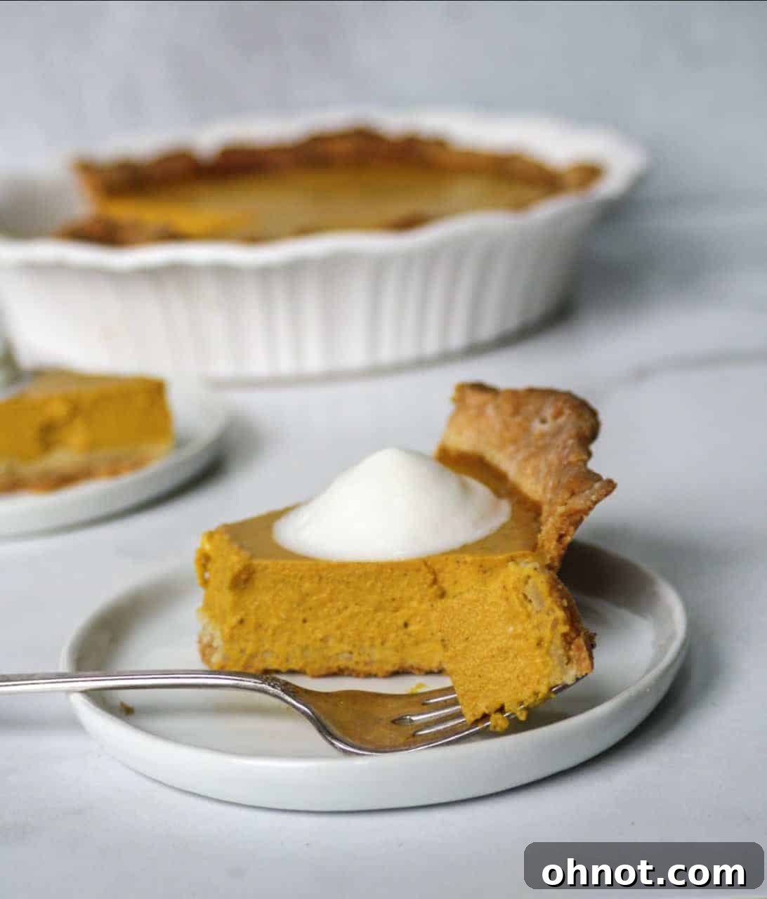 A slice of Paleo Pumpkin Pie topped with whipped coconut cream, ready to be enjoyed.