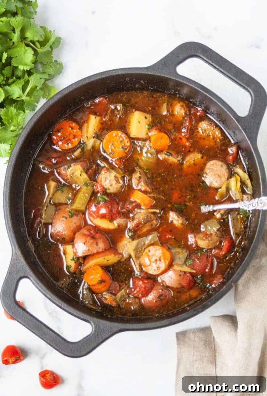 Two bowls of Paleo Sausage Cabbage Soup on a rustic wooden table, ready to be served.