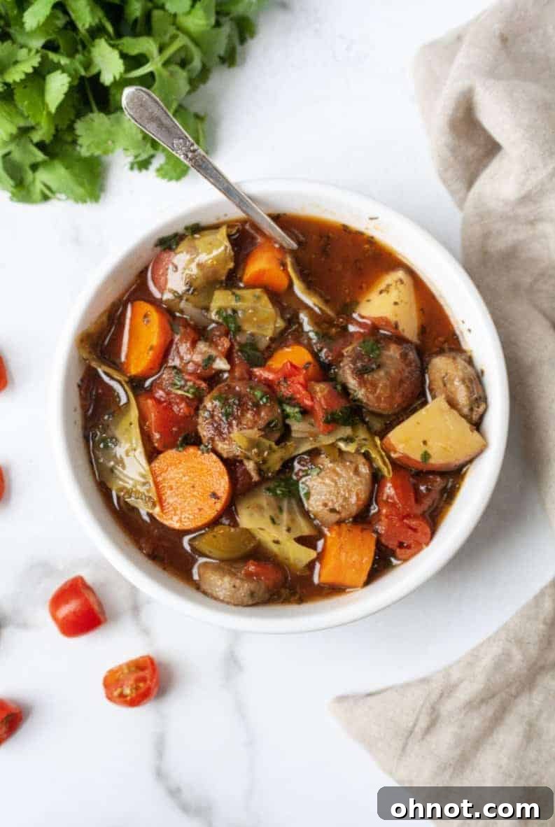 A close-up of a rustic bowl of Paleo Sausage Cabbage Soup, showcasing the ingredients.