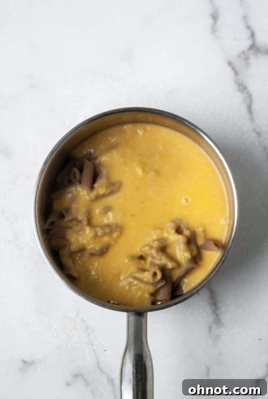 A serving of butternut squash mac and cheese with a fork, ready to eat.