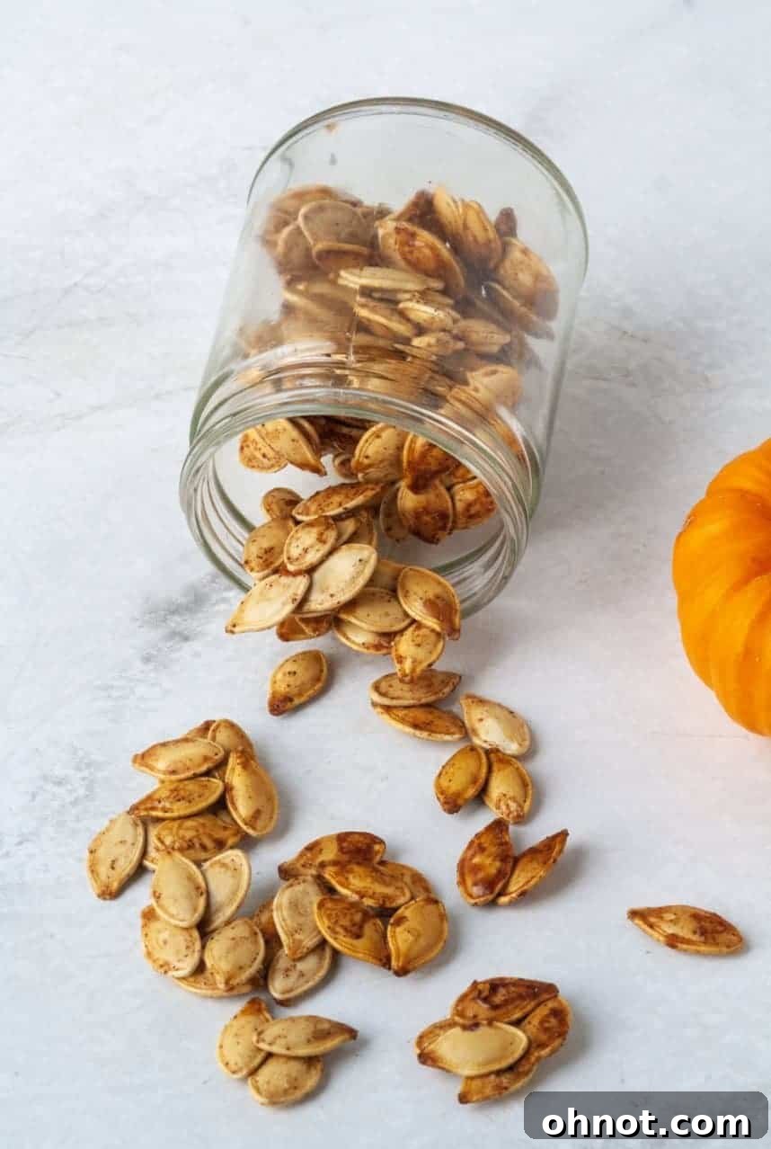 A rustic bowl filled with golden-brown roasted pumpkin seeds, with a few scattered on a wooden surface.