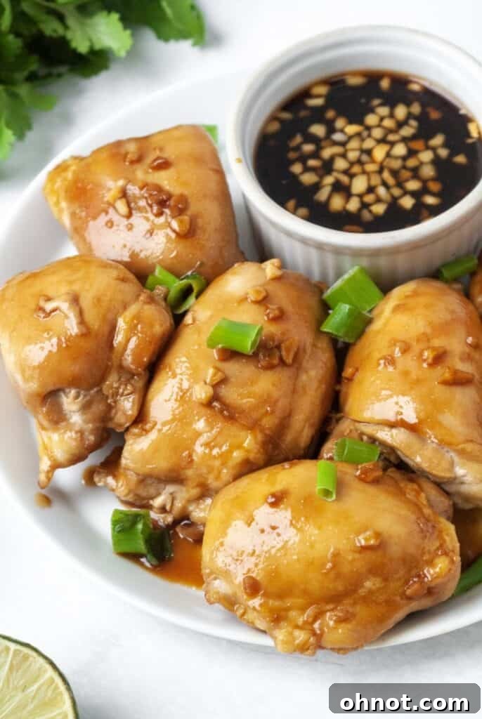 Close-up of Whole30 Garlic Ginger chicken on a white plate, showcasing the crispy skin and sauce.