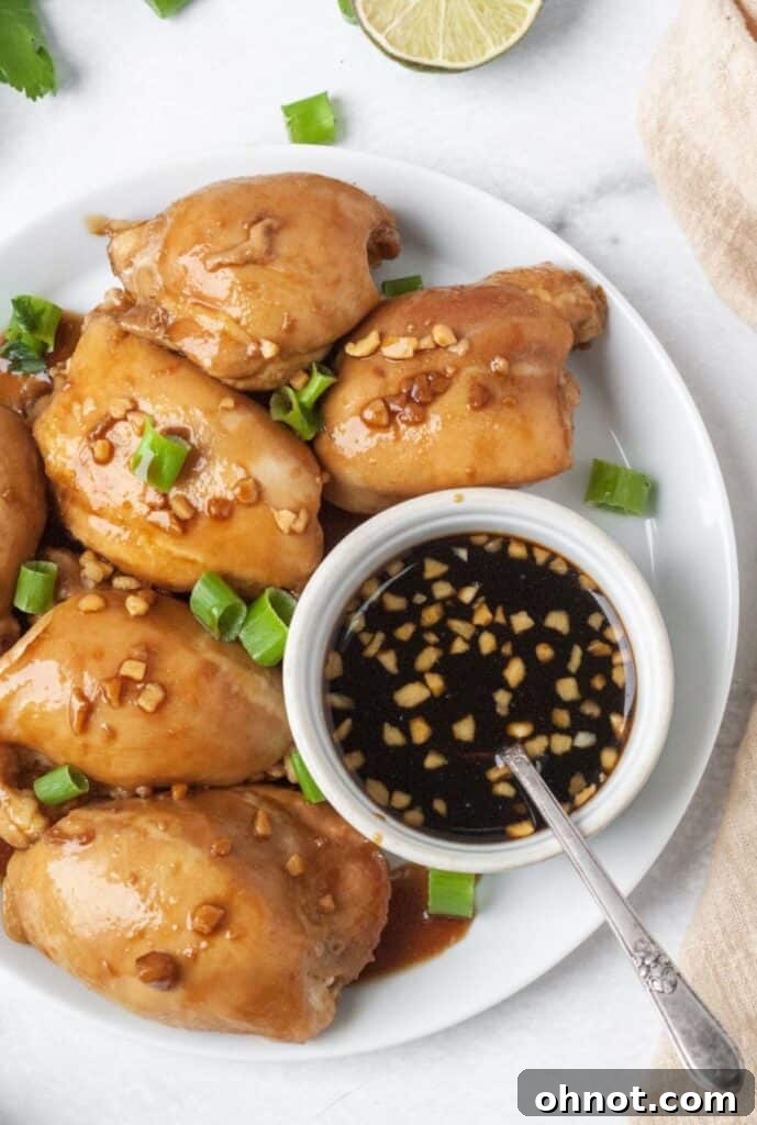 Overhead shot of Whole30 garlic ginger chicken with green onions on a white plate, ready to serve.
