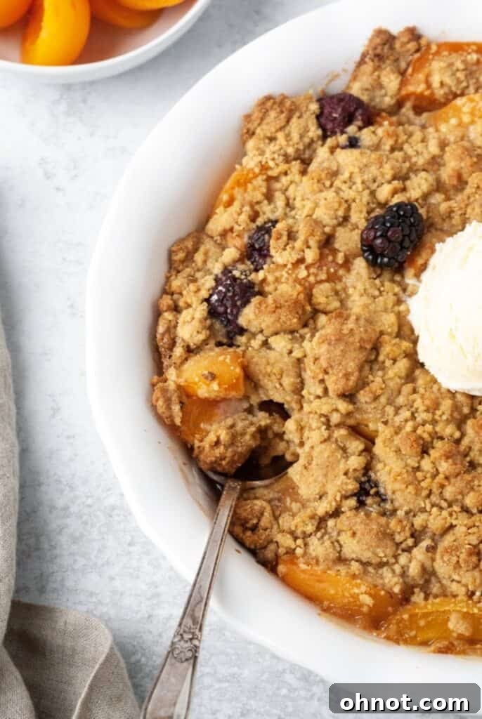 Paleo fruit cobbler with apricots and blackberries in a white pie dish, ready to be served.