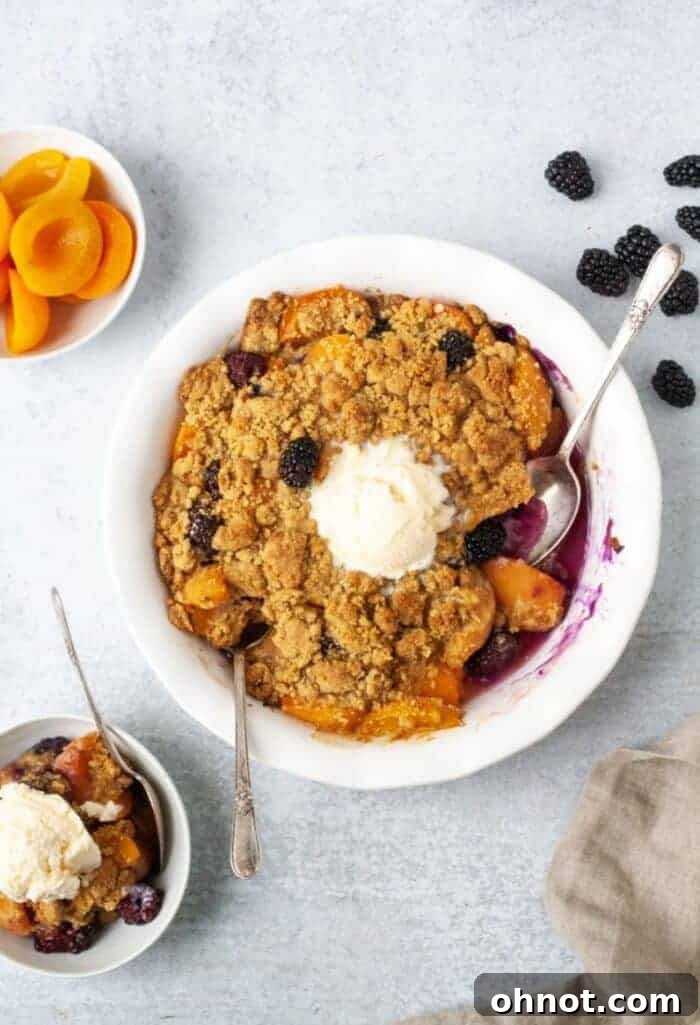Paleo Vegan Apricot Blackberry Cobbler baking in a white pie dish, showcasing its golden topping and bubbling fruit.