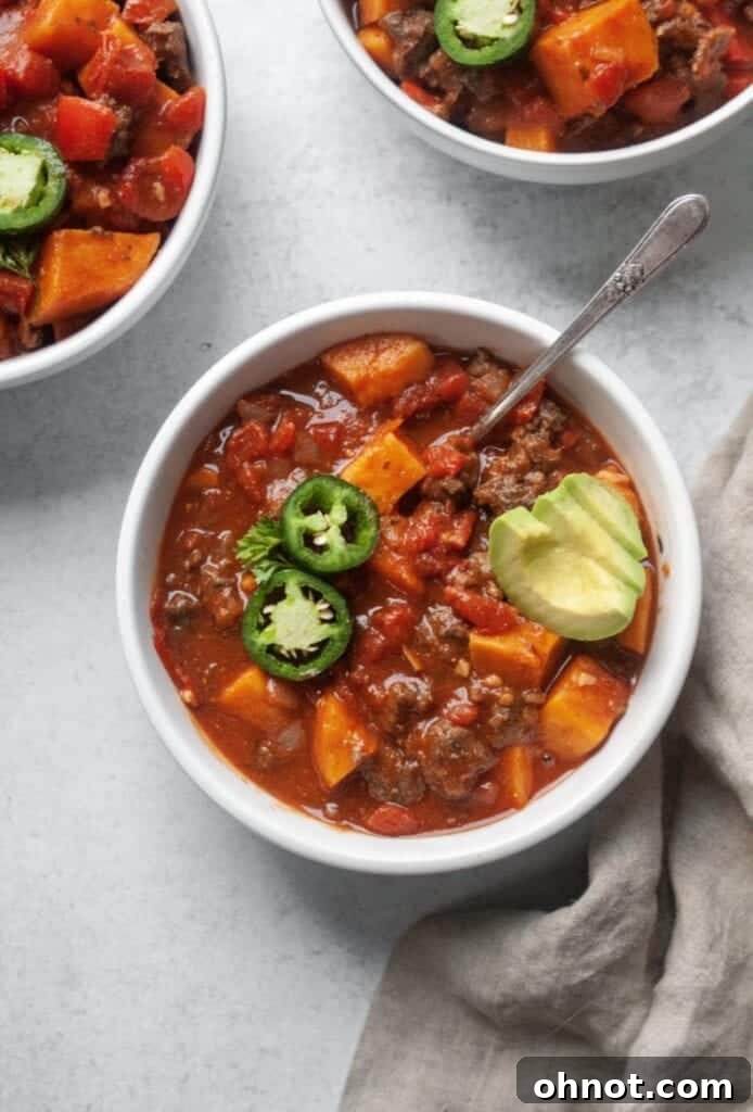 A vibrant bowl of Whole30 sweet potato chili, garnished with fresh herbs and avocado slices, ready to be enjoyed.