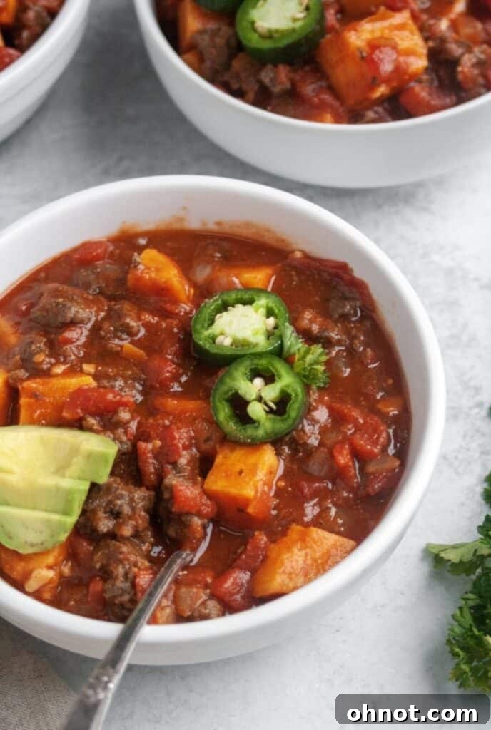 Two white bowls filled with steaming Whole30 Sweet Potato Chili, garnished with fresh cilantro.