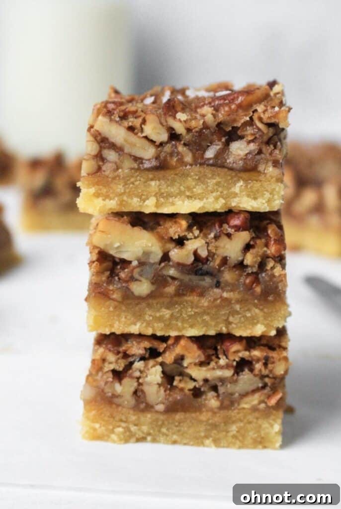 Several neatly sliced Paleo pecan pie bars arranged on a white backdrop, ready for serving.