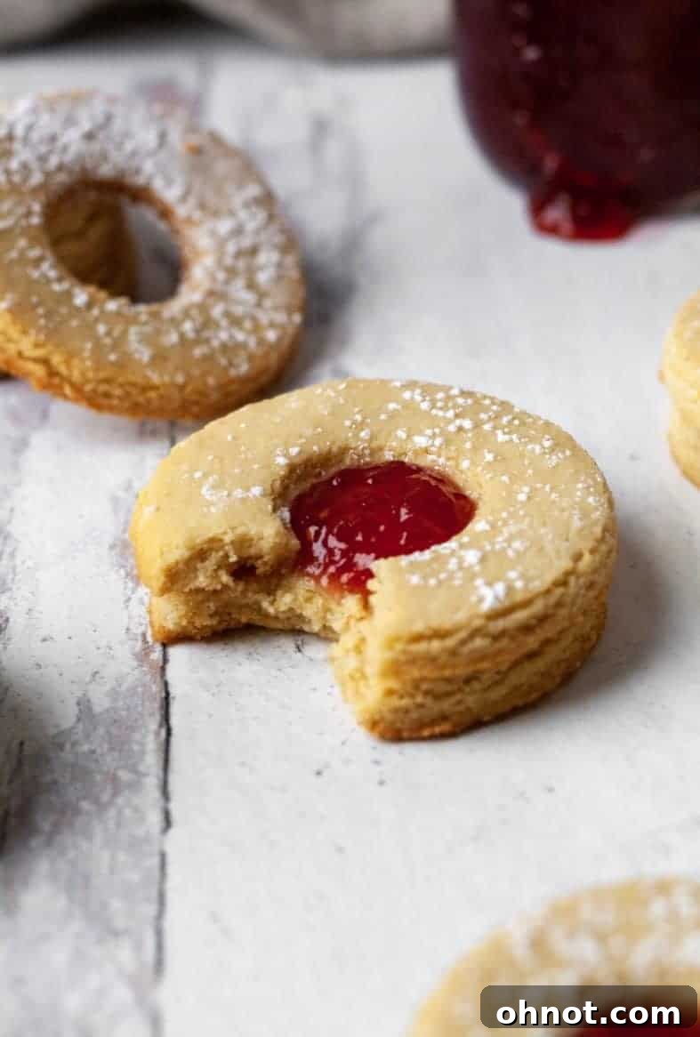 Freshly baked gluten-free Linzer cookie halves, some with a center cut-out and others whole, cooling on a wire rack.