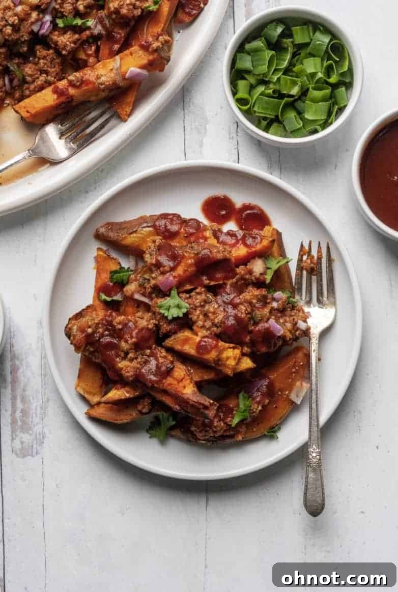 A bowl of Whole30 Chili Fries adorned with fresh parsley and a drizzle of BBQ sauce.