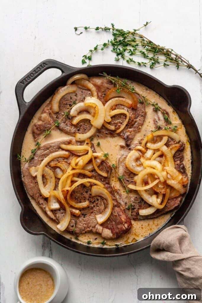 Tender Whole30 steak with gravy and caramelized onions in a cast iron skillet