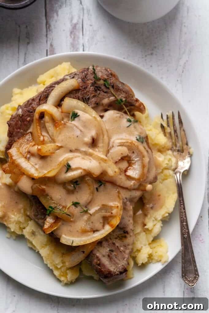 Ingredients for Whole30 Steak with Gravy laid out on a cutting board, including steak, onions, and spices