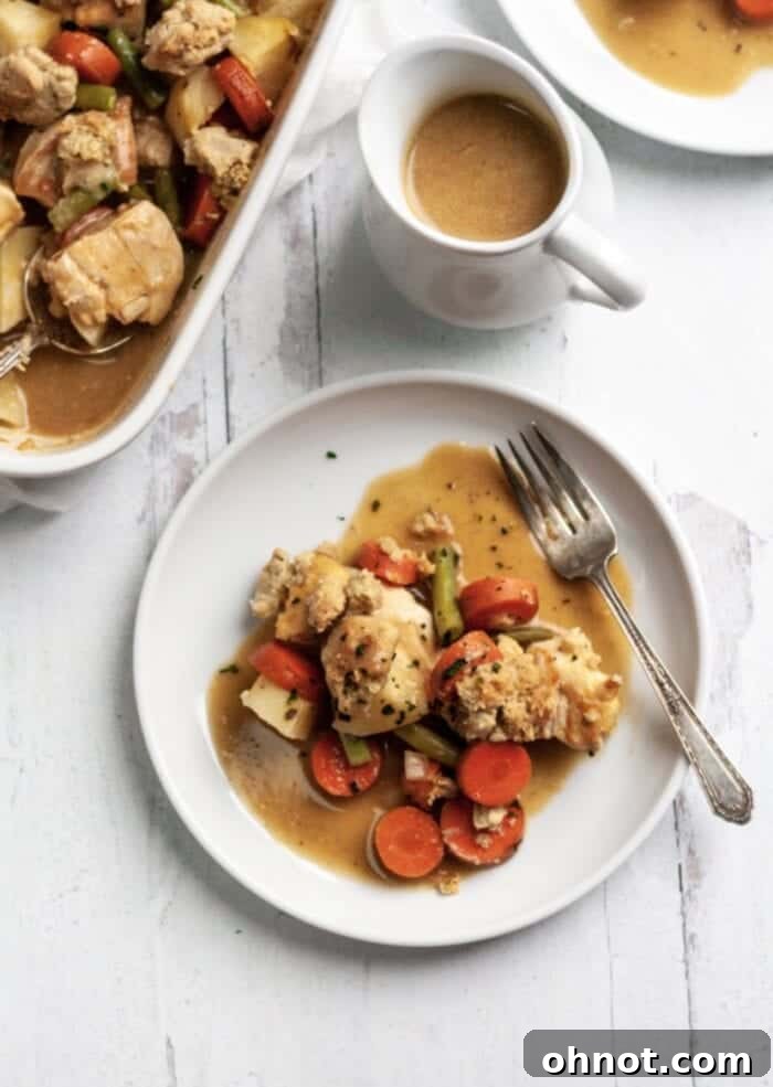 A close-up of Whole30 Chicken Pot Pie casserole on a white plate, showcasing the creamy filling and golden topping.