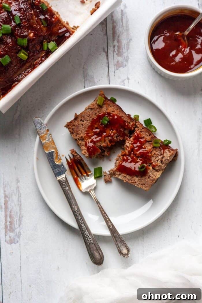 Sliced Whole30 Paleo Asian Meatloaf garnished with green onions, served on a plate.