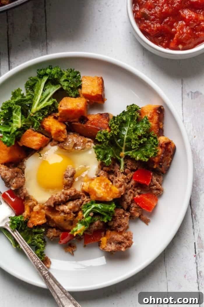 A colorful skillet breakfast hash with sweet potatoes, chorizo, and greens, topped with fried eggs.