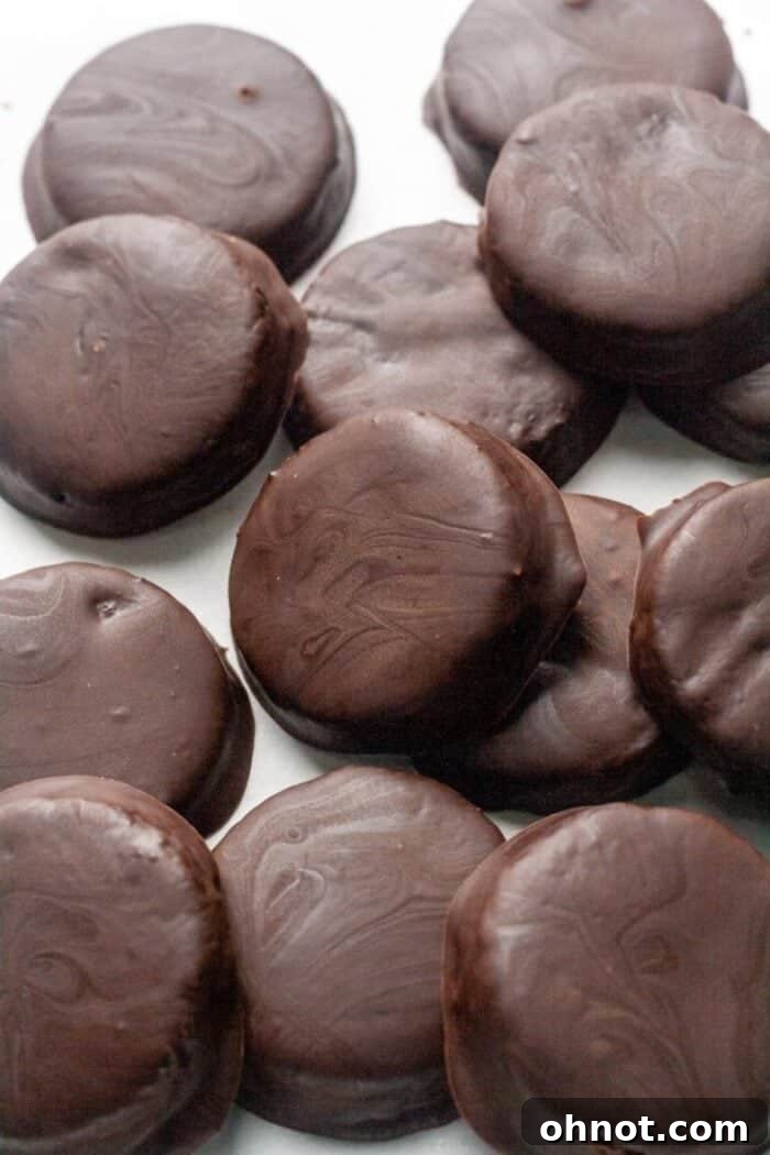 Crispy, homemade Gluten-Free Thin Mint cookies arranged neatly on a piece of parchment paper, showcasing their dark chocolate coating and thin profile.