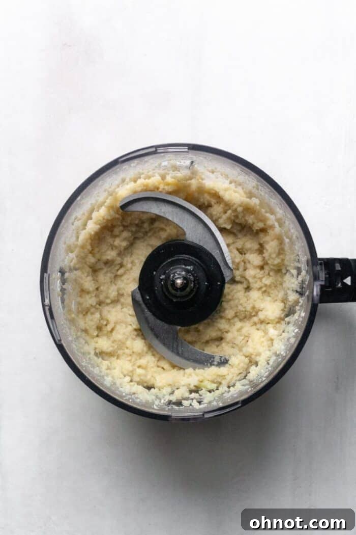 A food processor filled with Whole30 mashed cauliflower, perfectly blended.