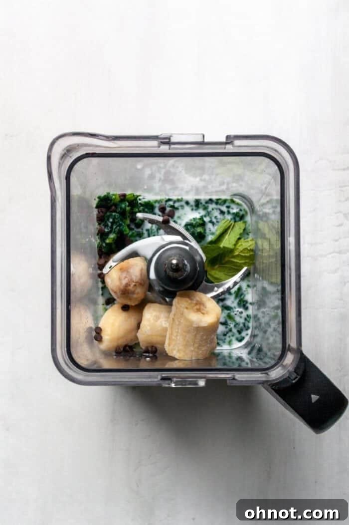 A blender with Mint Chocolate smoothie ingredients inside.