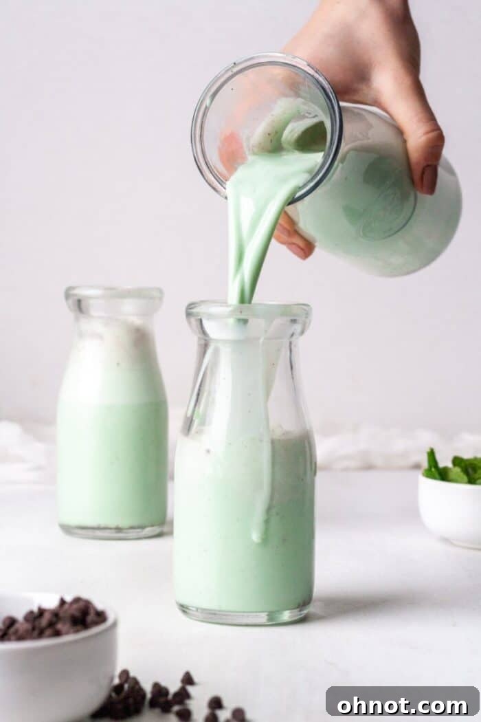 Mint chocolate smoothie being poured into a glass jar.