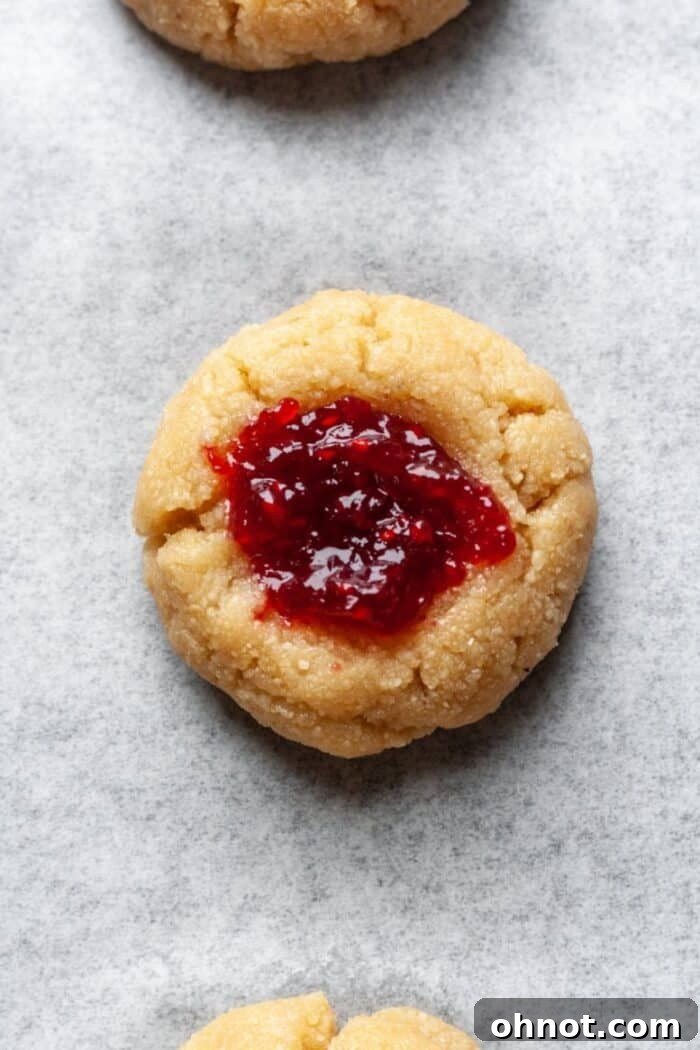 Almond flour thumbprint cookies filled with luscious raspberry jam, ready for baking.