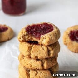 A stack of almond flour thumbprint cookies filled with jam.