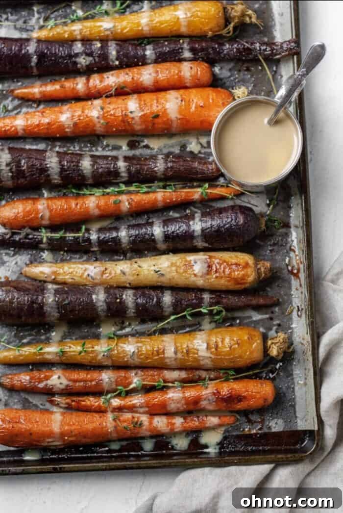 Vibrant rainbow carrots with a creamy maple tahini sauce drizzled over.