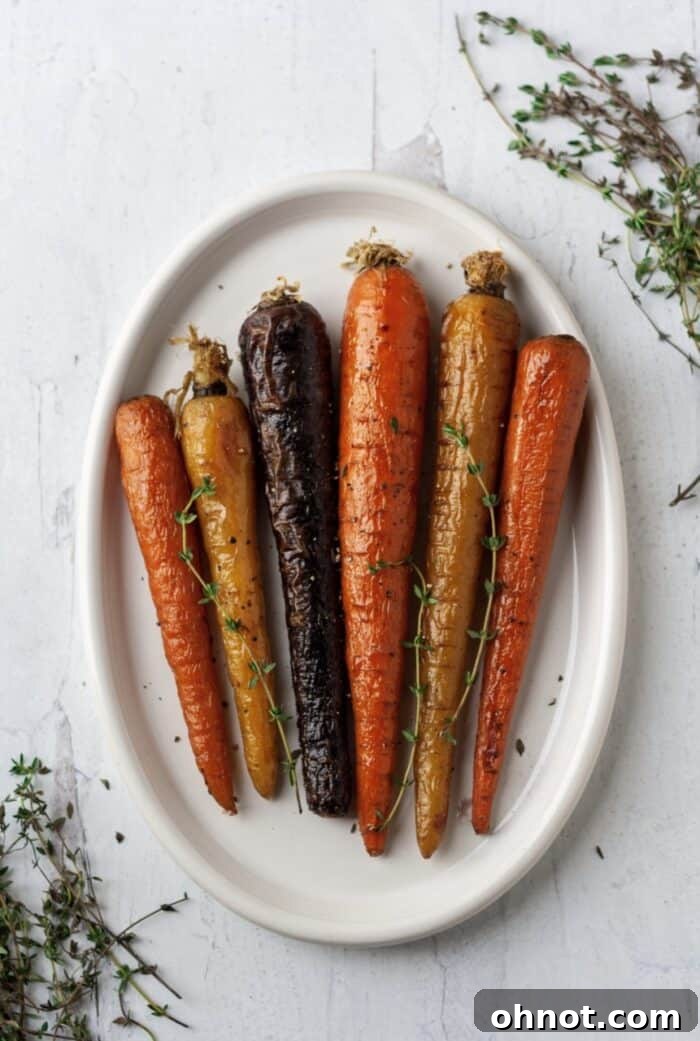 Air fryer carrots on a white plate, garnished with rosemary.