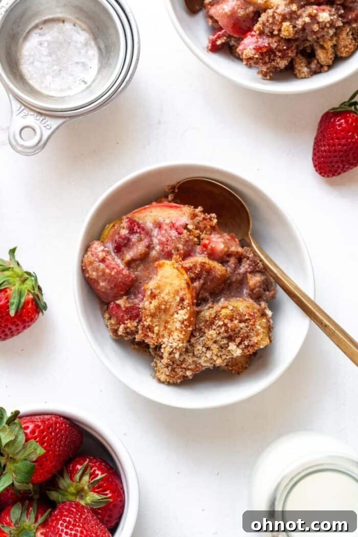 A generous serving of apple strawberry crumble in a bowl, steam gently rising.
