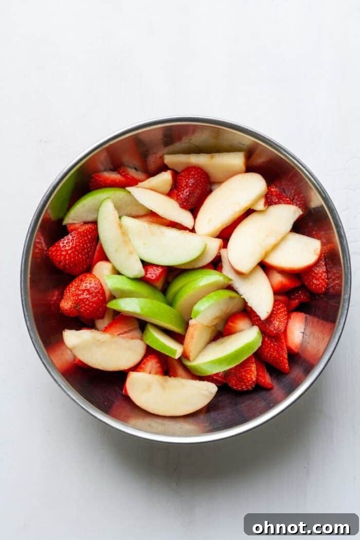 A vibrant bowl filled with freshly sliced strawberries and apples, perfectly prepped for the crumble filling.