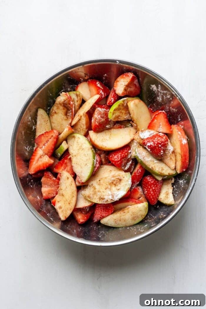 A large bowl of fresh fruit tossed with filling ingredients, glistening and ready for assembly.