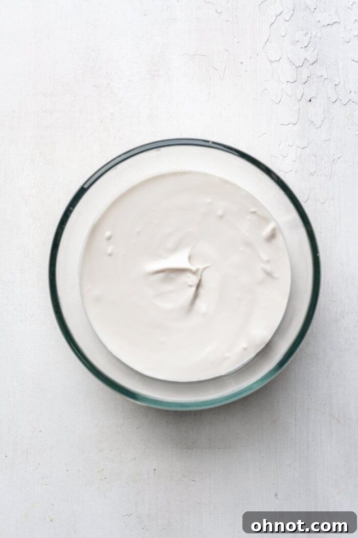 Vegan vanilla frosting whipped to perfection in a glass mixing bowl.