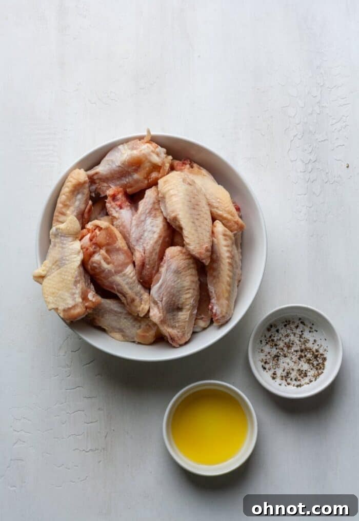 Frozen chicken wings coated with olive oil, salt, and pepper in a white bowl, ready for the air fryer.