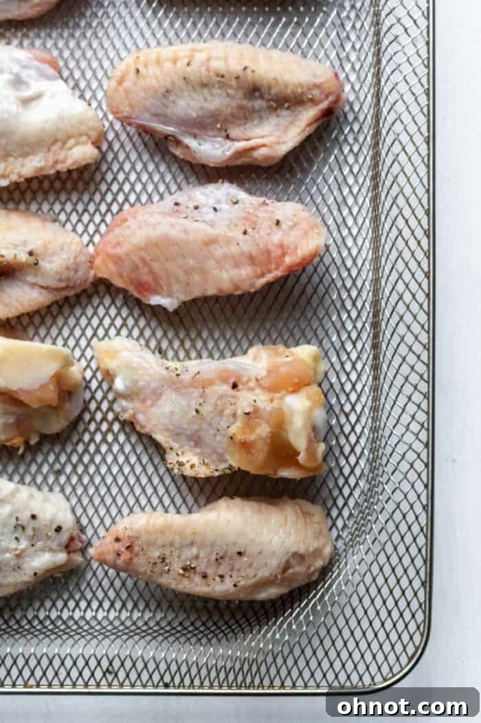 Frozen chicken wings neatly arranged in a single layer on an air fryer basket.