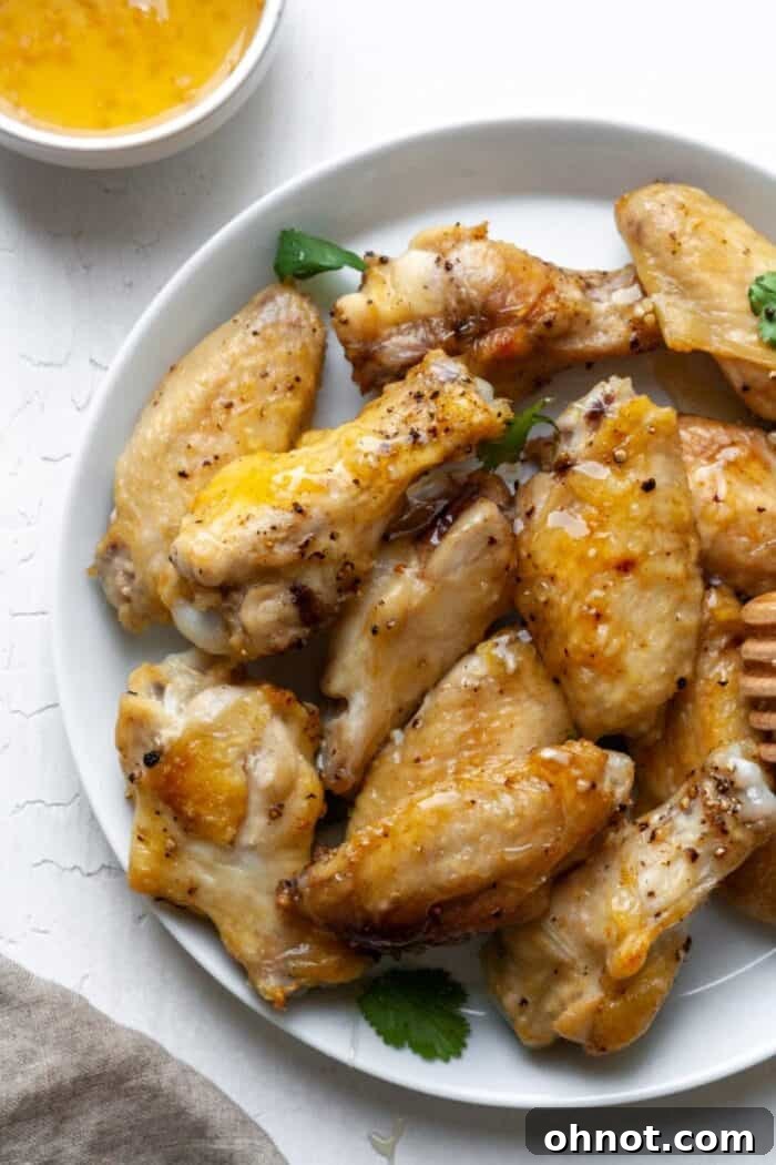 A serving platter filled with glistening honey garlic air-fried chicken wings, garnished and ready.