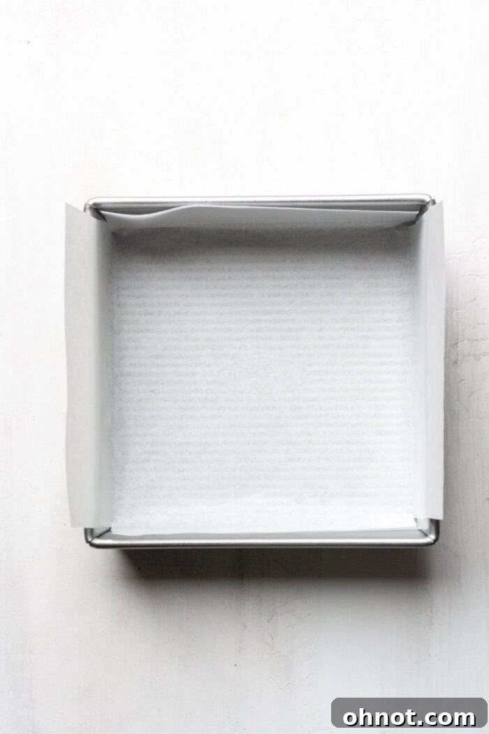 An 8x8 inch baking pan meticulously lined with parchment paper